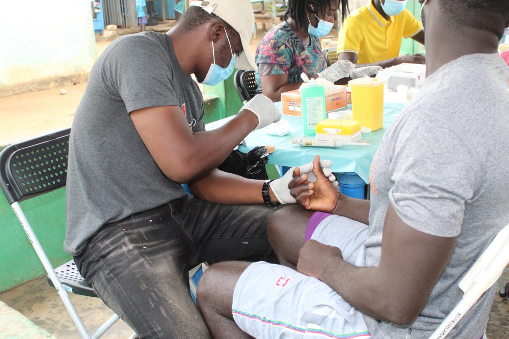 A potential study participant being pricked on the finger to test for the presence of circulating filarial antigen (CFA)